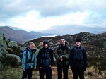 Ruth, Phil, Mark and Zak shiver in the wind atop King's How, in front of Derwent Water and Skiddaw